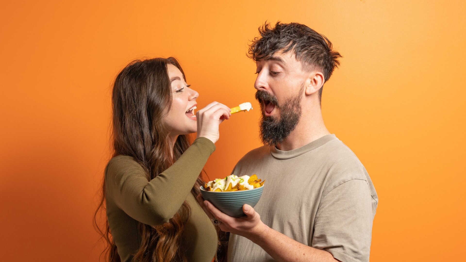 Woman feeding man a chip with SideCar mayo on it