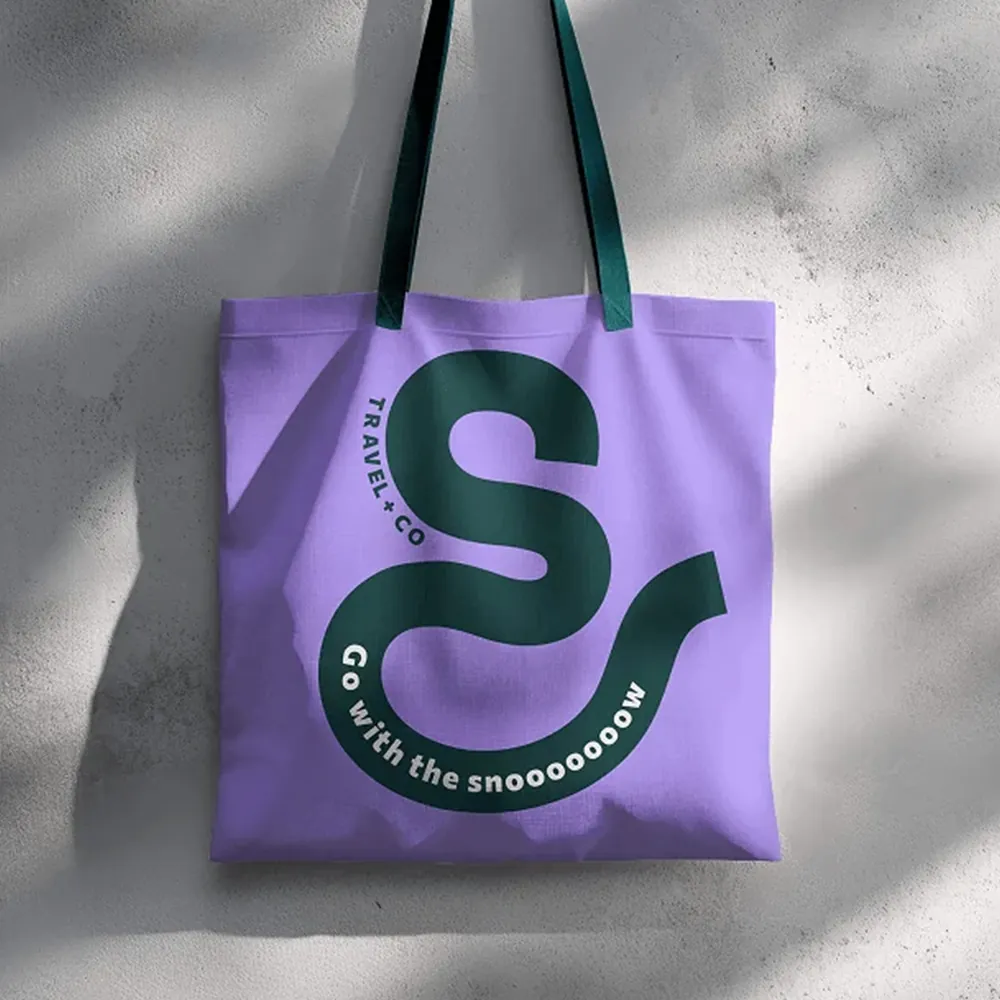Travel&co branded purple tote bag with dark green s-shaped logo and slogan ‘go with the snooooooow’, designed by downing creative marketing.