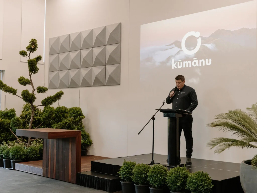 Speaker at event with greenery backdrop