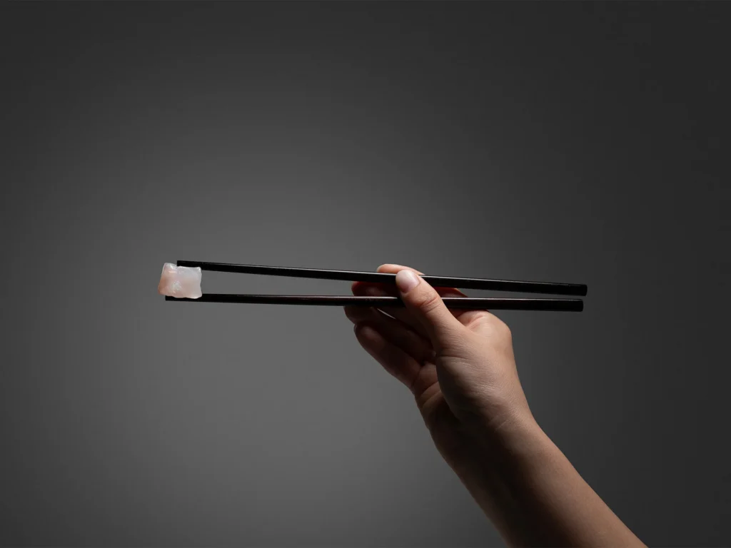 Hand holding chopsticks with food
