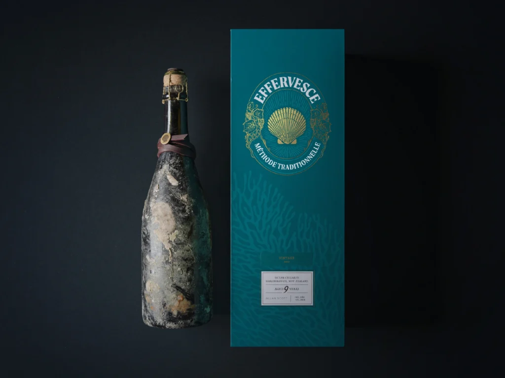 Ocean-cellared Effervesce wine bottle next to a dark teal Effervesce display box by Allan Scott.