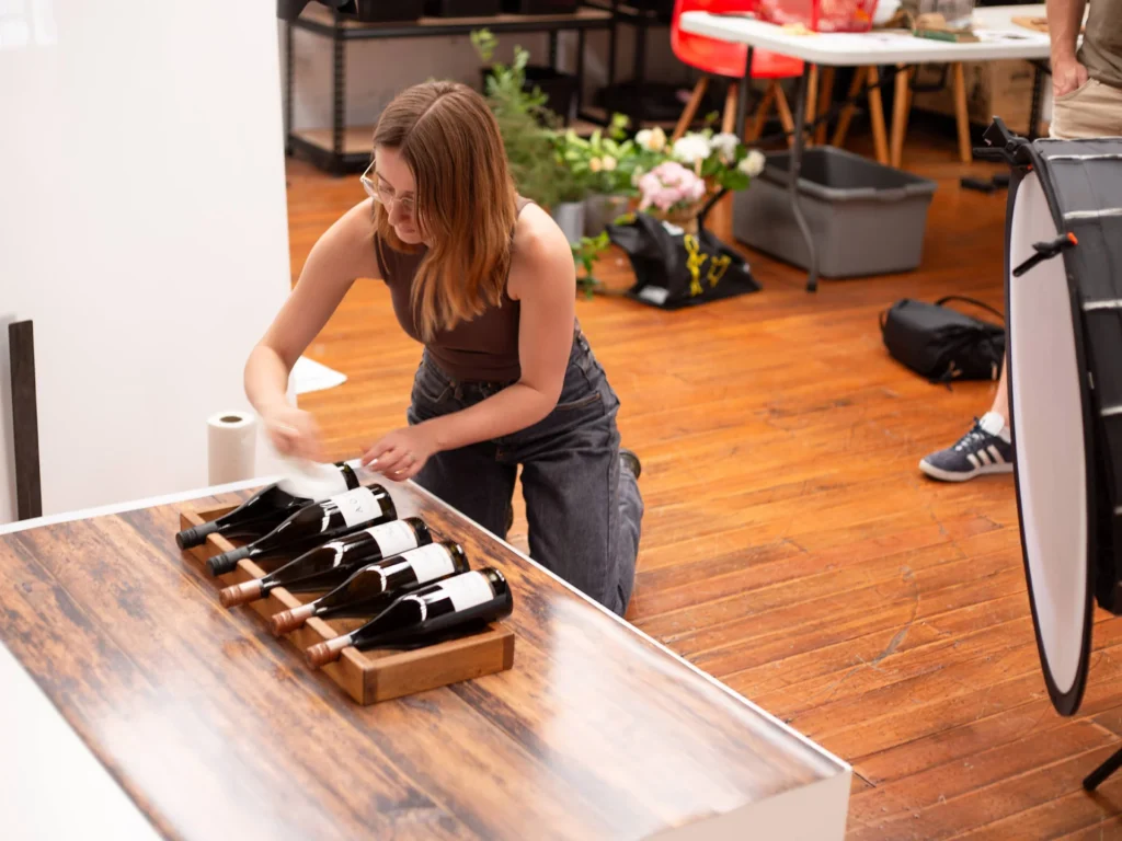 Person arranging wine bottles on table