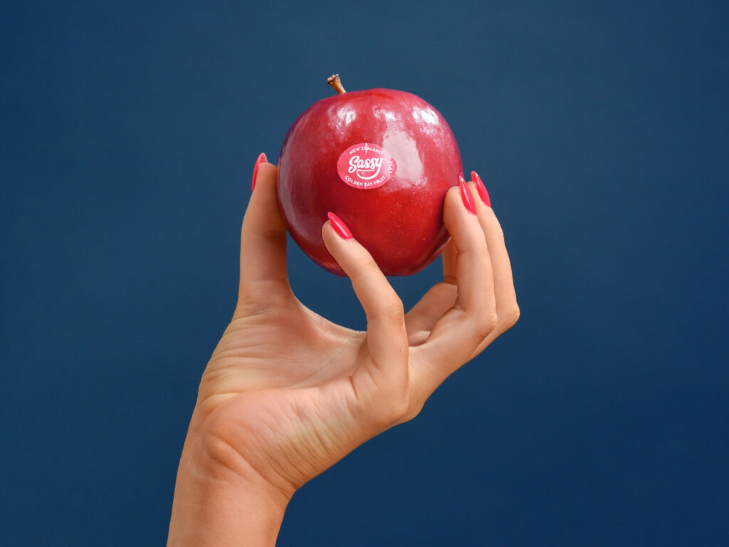 A hand holding an apple on a blue background