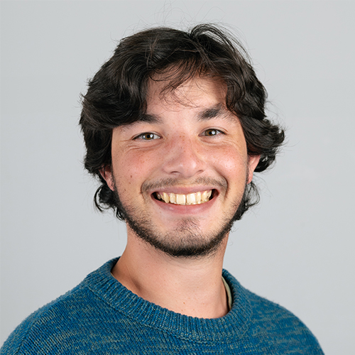 Studio portrait of Josh, Web Developer at Downing, with dark curly hair smiling.