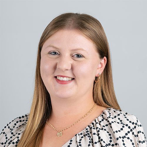Studio portrait of Kaylie, Creative at Downing, smiling in a patterned top.