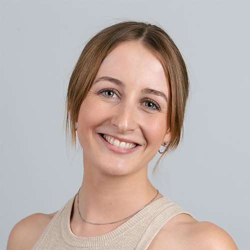Studio portrait of Nadia, Digital Producer at Downing, smiling with a neutral background.