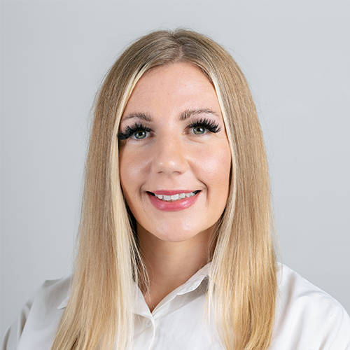 Studio portrait of Sinead, Marketing Manager at Downing, smiling with long blonde hair.
