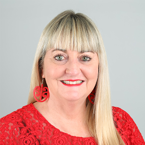 Studio portrait of Vanessa, Director and Sales at Downing, with blonde hair and red earrings.