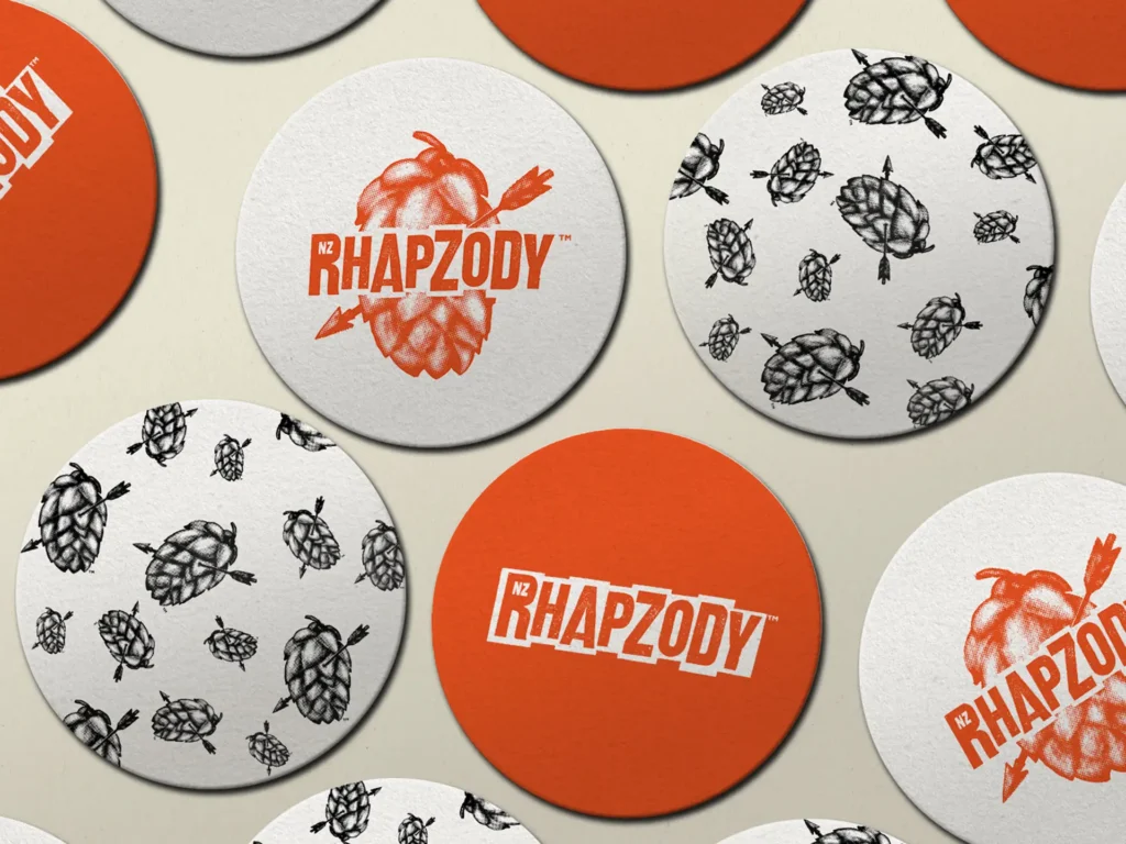 Collection of circular beer coasters featuring illustrated hop icons and orange Rhapzody brand logos.