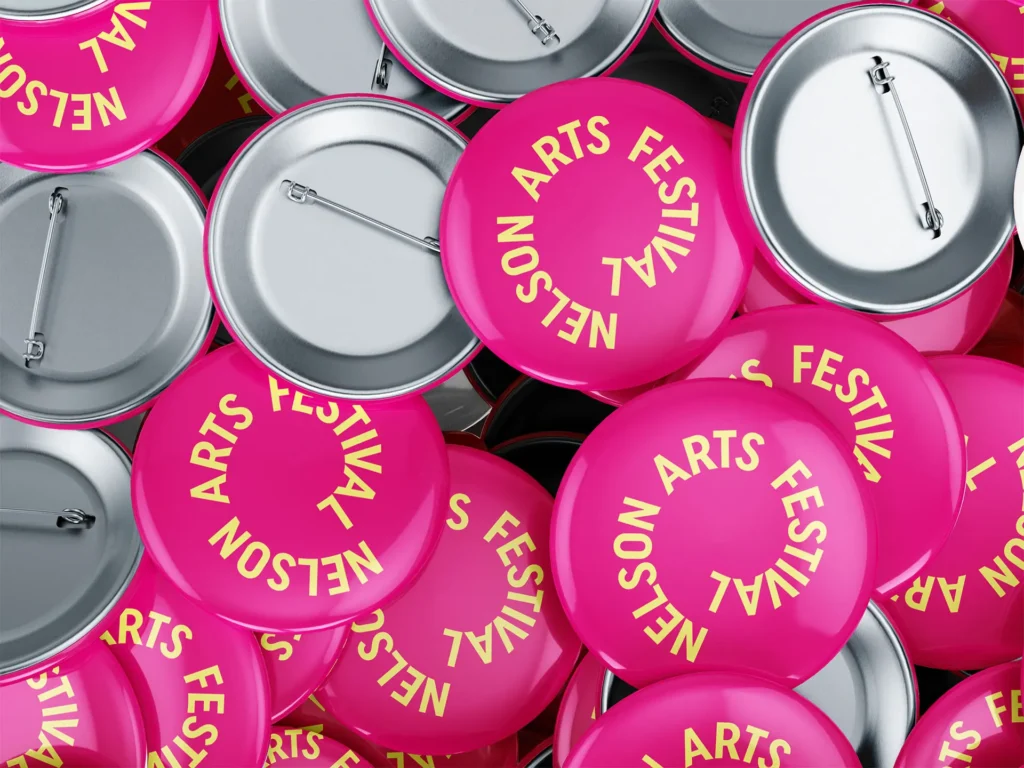 nelson arts festival magenta and yellow logo on badges