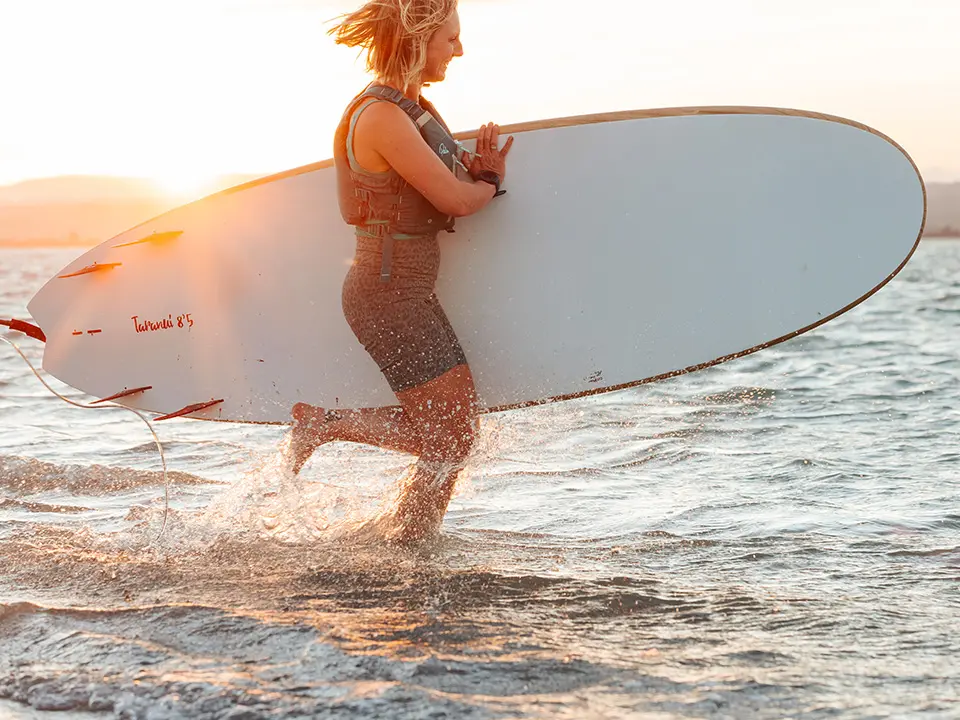 Woman running into water on surfboard- Downing art directed photography