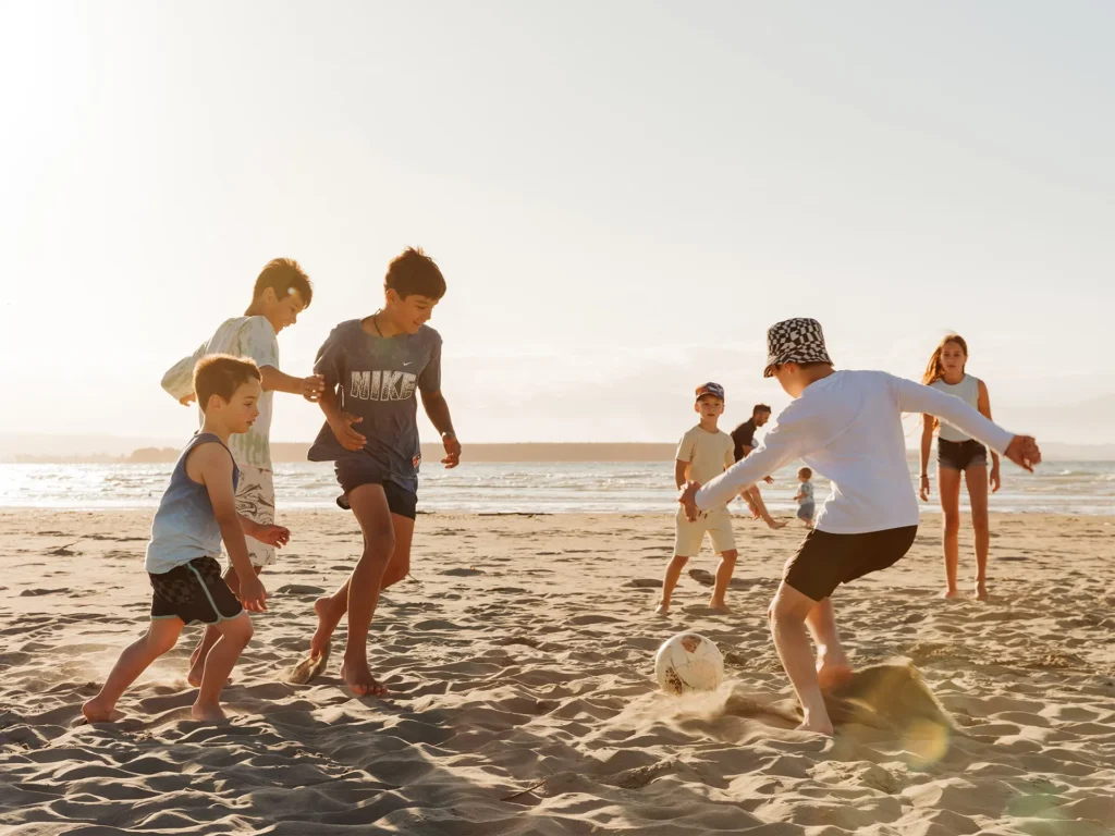 kids playing football on Tāhuna Beach - Downing art directed photography